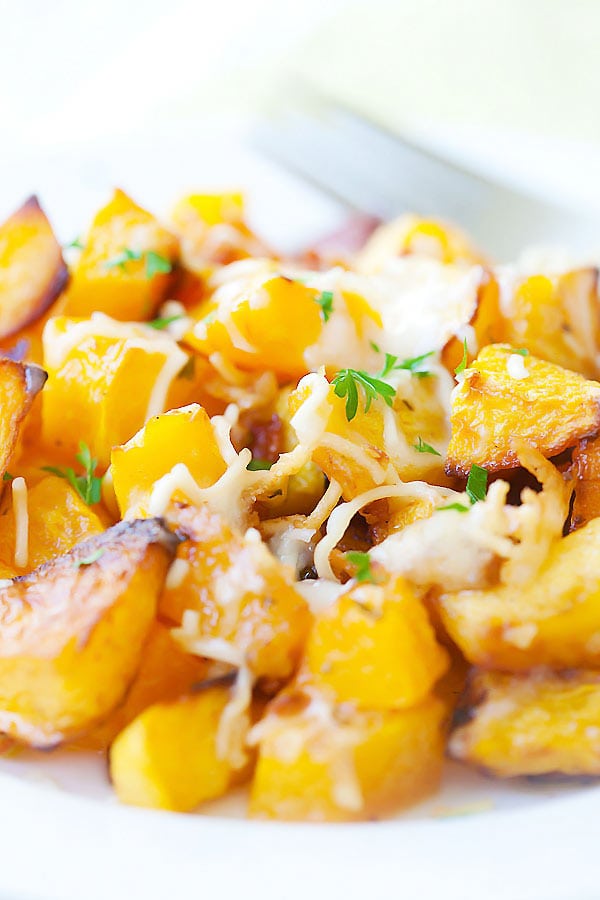 Roasted butternut squash cubes with garlic, parsley, and Parmesan cheese on top.