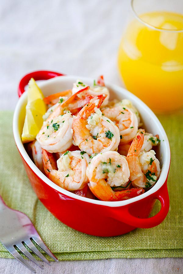 Lemon Garlic Shrimp in a serving dish, topped with parsley and a lemon wedge on the side.