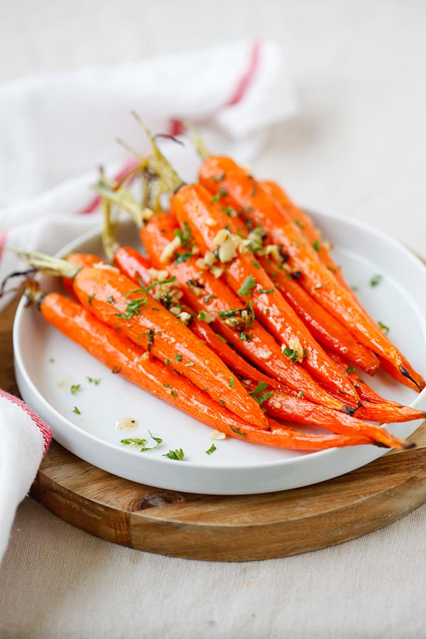 Roasted carrots with honey, butter and garlic on a white plate, garnished with chopped parsley.