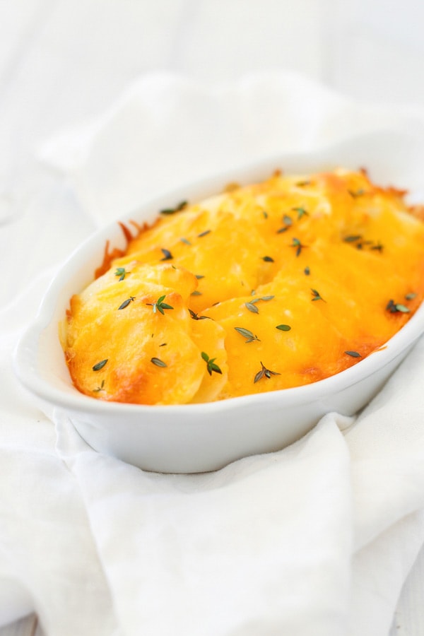 Easy and quick creamy Scalloped Potatoes recipe with cheese in a baking dish.