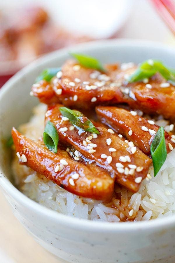 Teriyaki chicken with steamed rice, teriyaki sauce, white sesame and chopped scallion in a Japanese bowl.