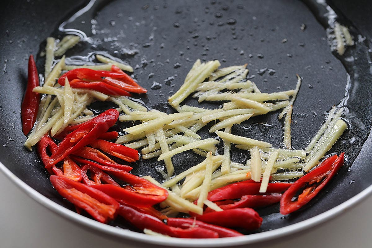 Stir frying ginger and chili in a skillet. 