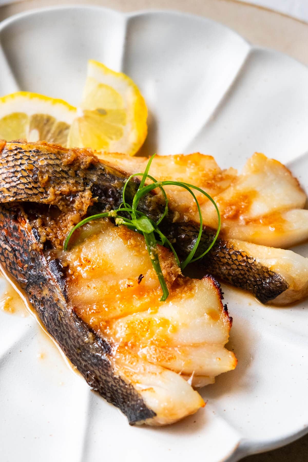Oven baked sea bass fillet recipe served with lemon wedges. 