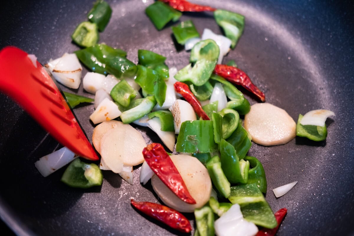 Add ginger, green bell pepper, onion and dried chilies to the wok, and stir-fry until aromatic. 