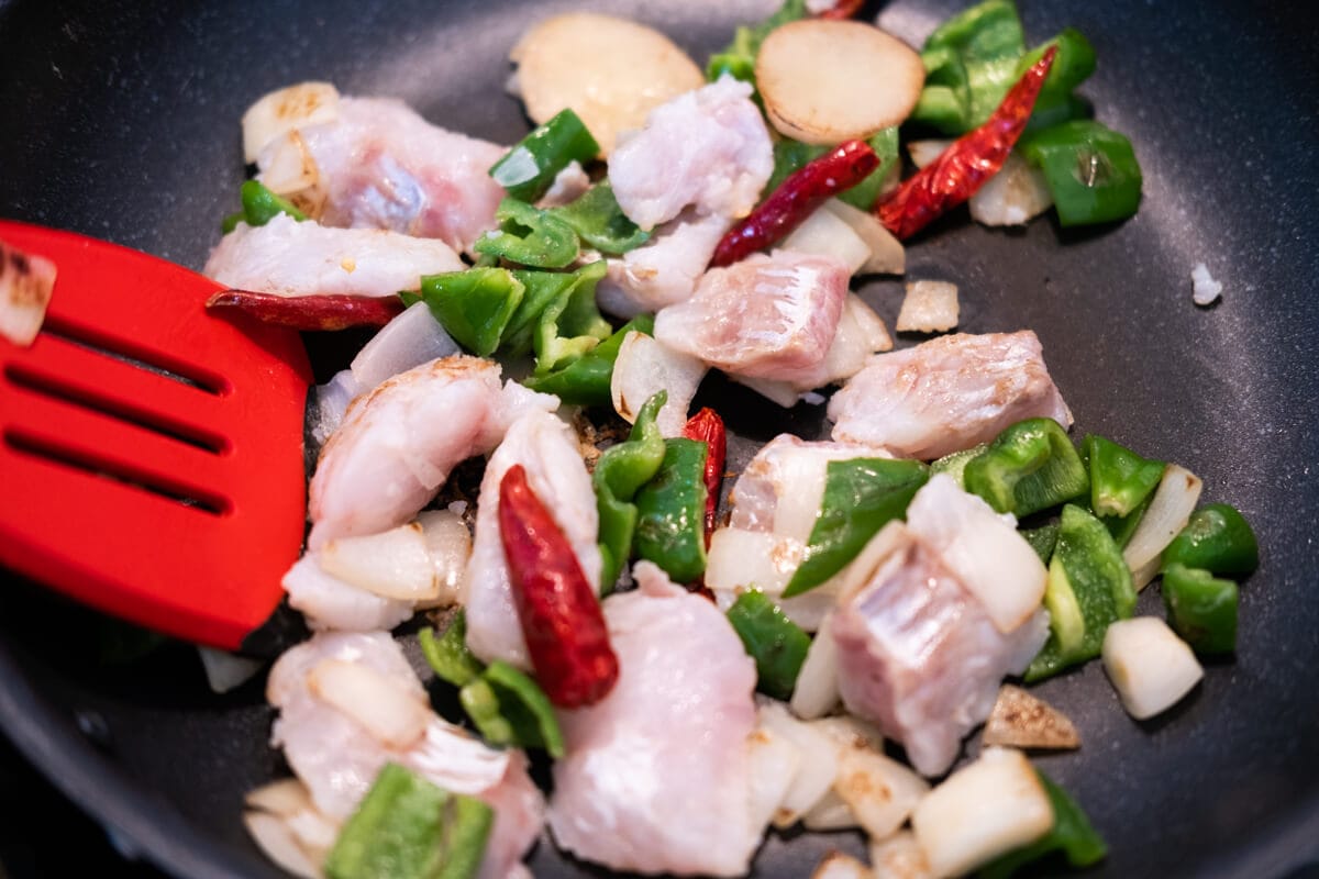 Add the fish to the wok and stir-fry until it is half-cooked.