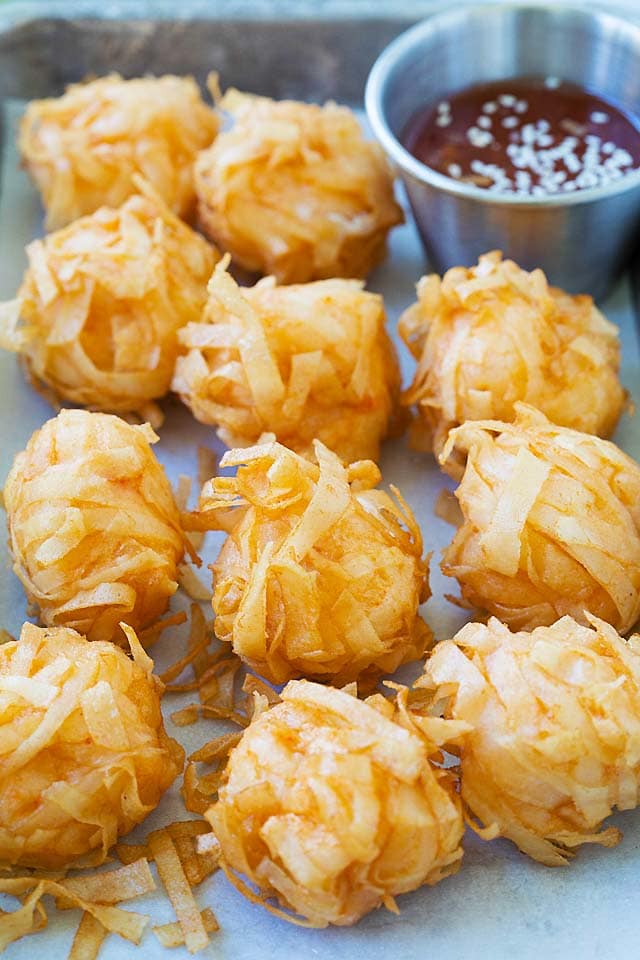 Crispy fried shrimp balls on a serving platter with dipping sauce.