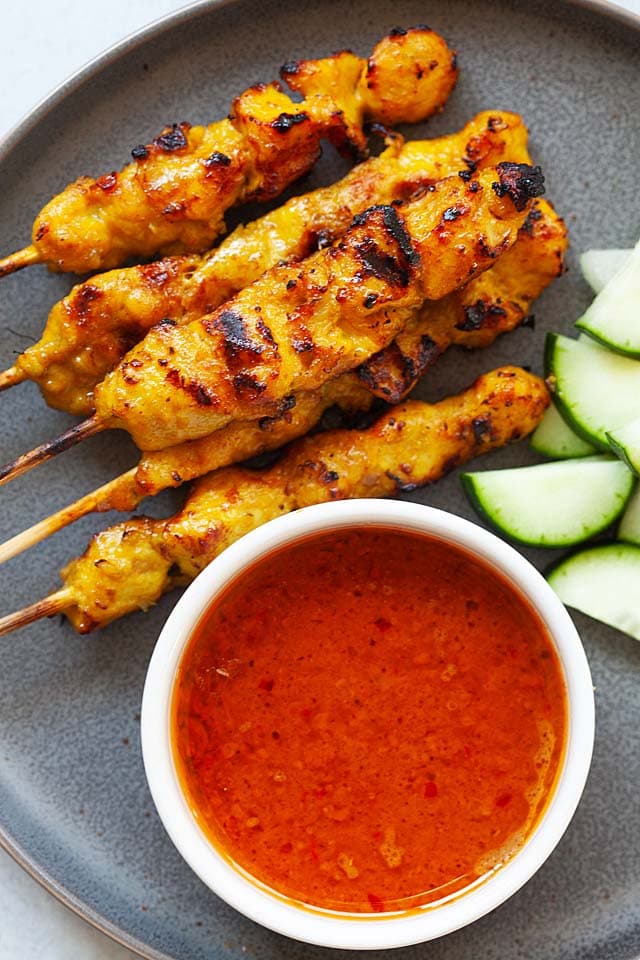 Chicken satay with peanut sauce on a plate.