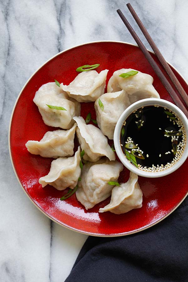 Easy Chinese pork and chive dumplings in a plate with a side of dipping sauce.