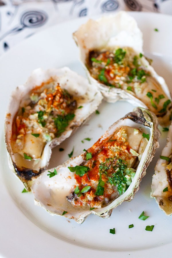 Easy grilled oyster on half shell with garlic, butter, parsley and paprika serve in a plate.