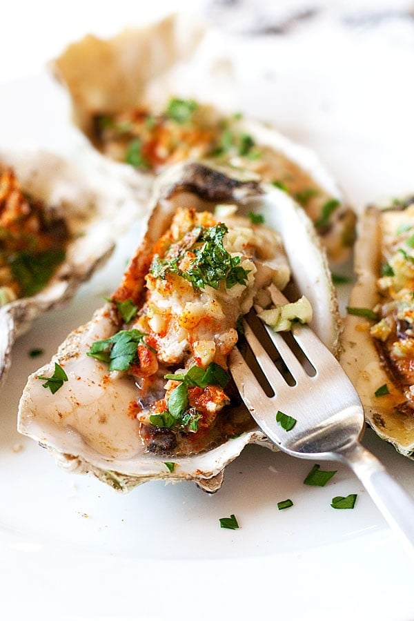 Close up oyster on the half shell poked with a fork.