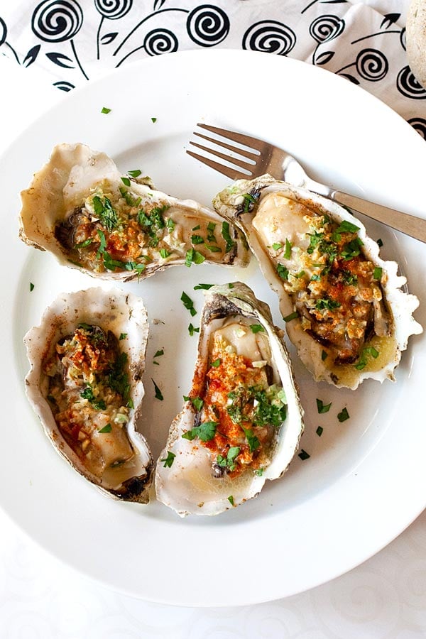 Top down view of grilled oysters marinade with garlic, butter, parsley and paprika, ready to serve.