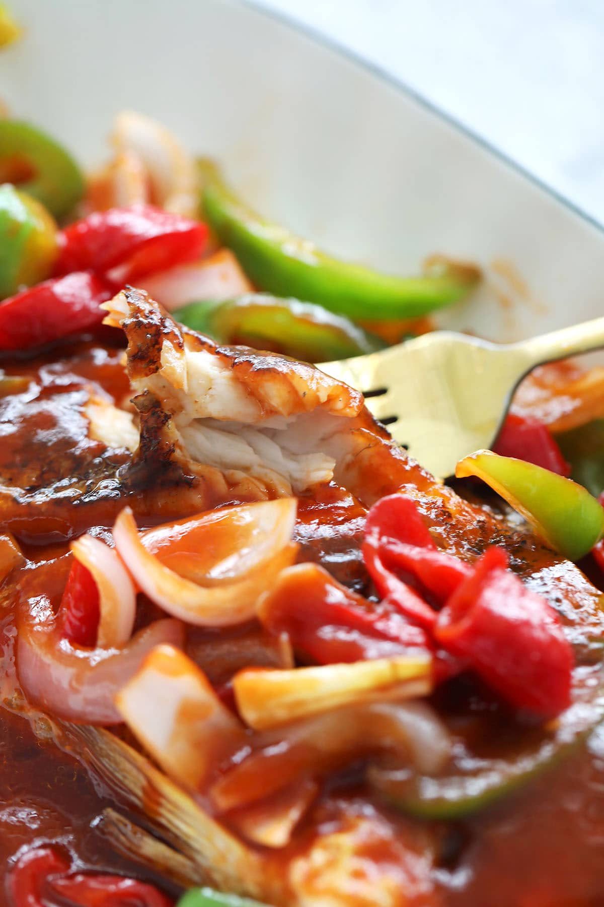 Forking a piece of fish fillet from the sweet and sour fish dish. 