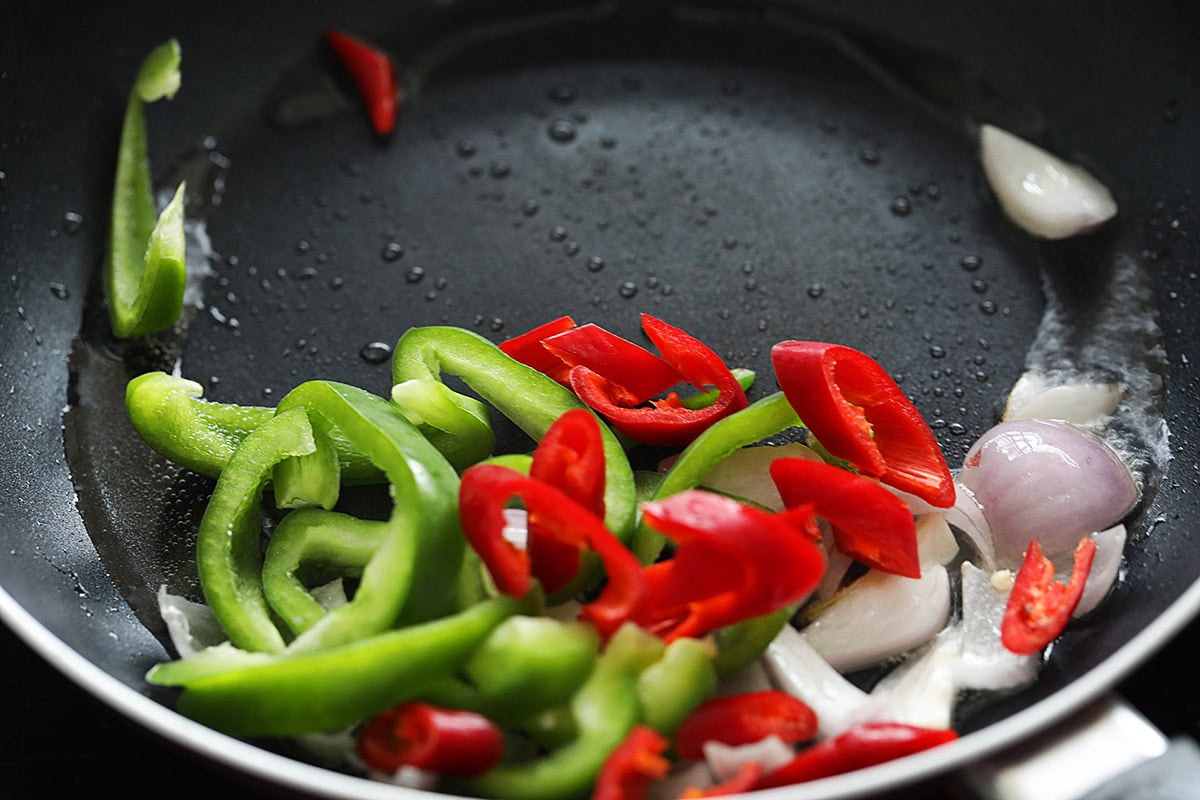 Stir frying onion, green bell pepper and red chili in the skillet. 