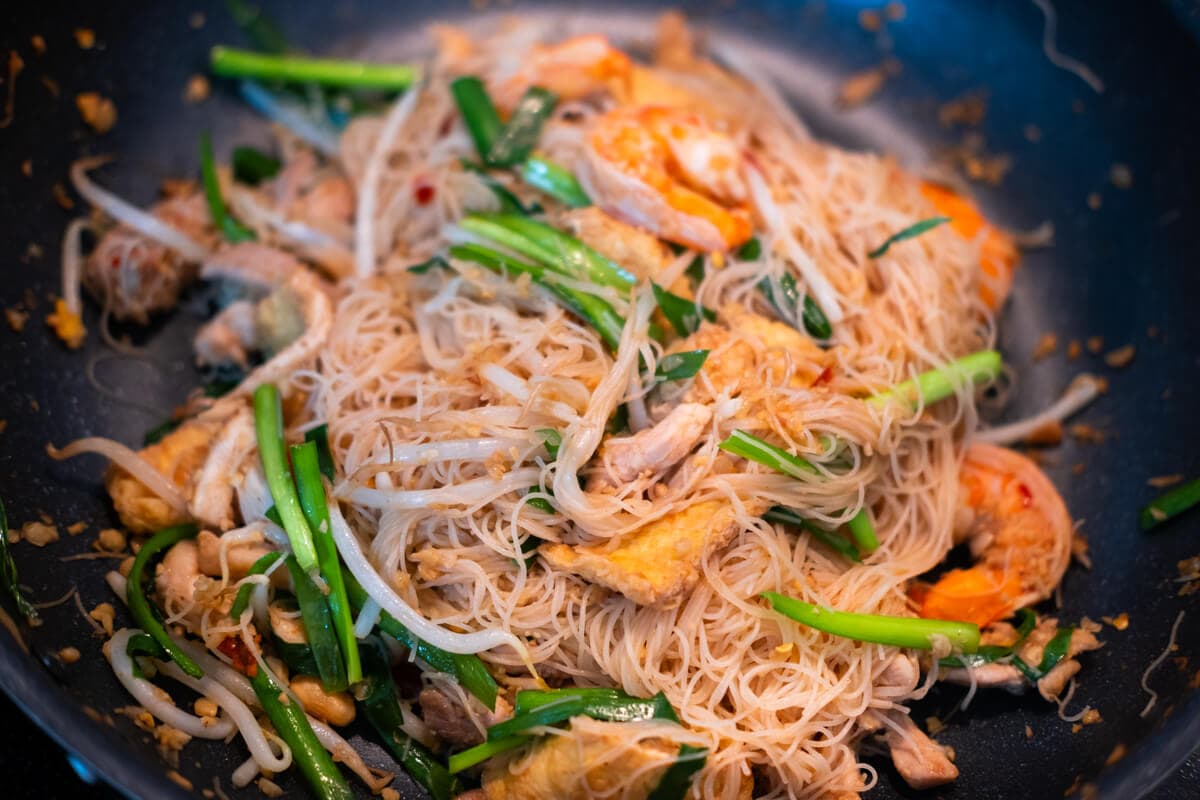 Rice vermicelli, bean sprouts and Chinese chives with the other ingredients in the wok. 
