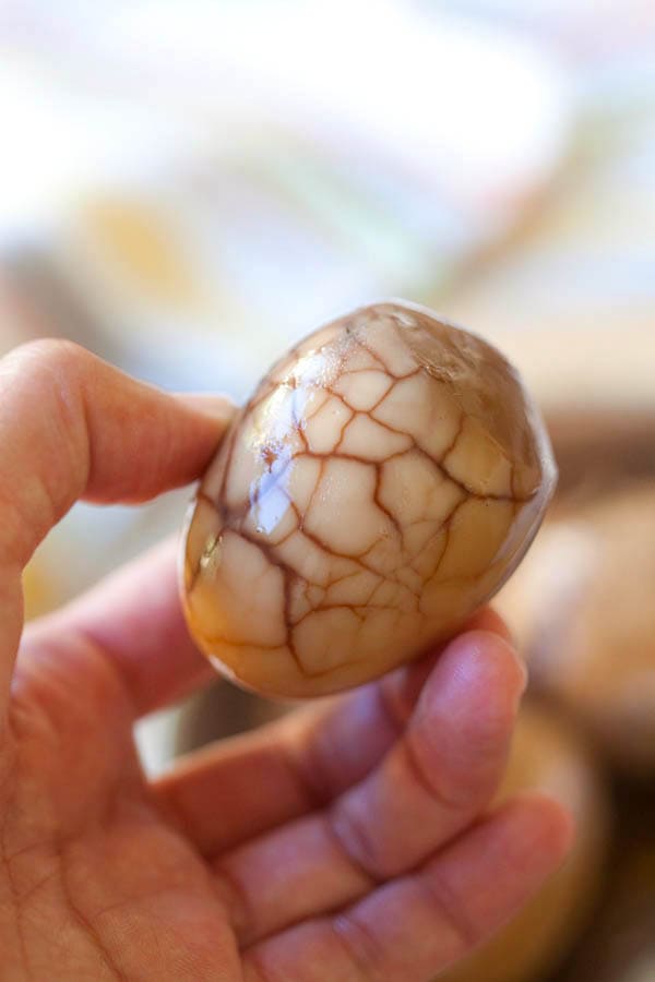 A hand holding peeled marbled brown tea eggs.