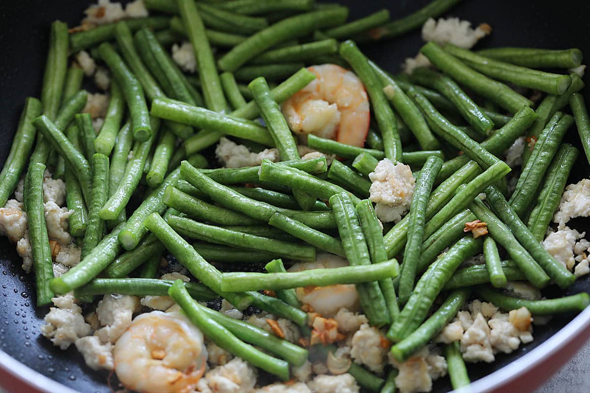 Adding long beans to a skillet to make Chinese long beans recipe. 