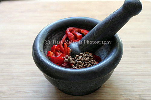 Sambal Belacan ingredients mixed in mortar and pestle for grinding and pounding process.