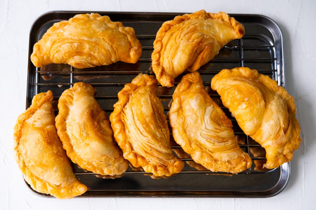 Deep fried Malaysian curry puffs on a cooling rack. 