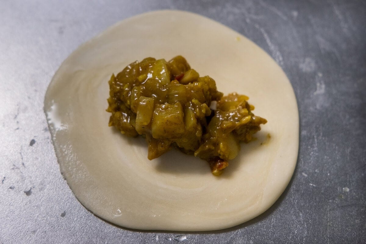 Wrapping curry puff pastry with chicken and potato filling. 