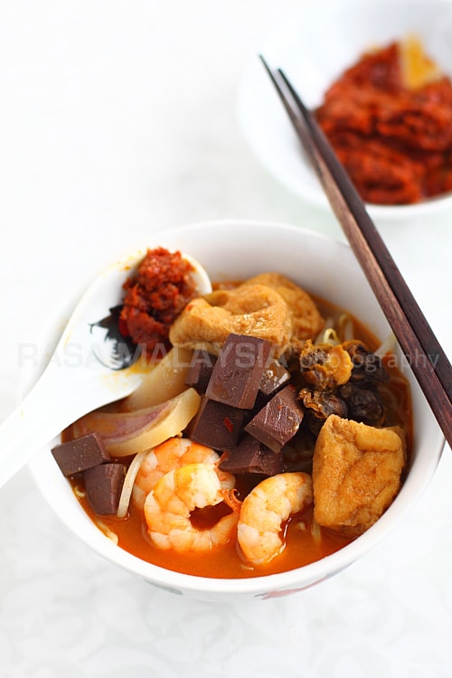 Penang Curry Mee recipe - With toppings many would consider bizarre: pig’s blood cubes (they taste like tofu except that they are maroon in color), bloody cockles, soaked cuttlefish slices, shrimp, and tofu puffs. | rasamalaysia.com