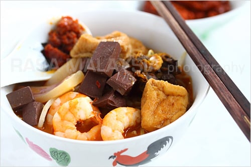 Penang Curry Mee recipe - With toppings many would consider bizarre: pig’s blood cubes (they taste like tofu except that they are maroon in color), bloody cockles, soaked cuttlefish slices, shrimp, and tofu puffs. | rasamalaysia.com