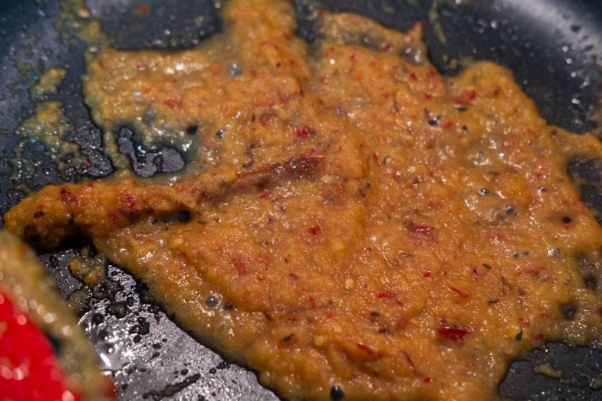 Cinnamon stick and spice paste in a pan.