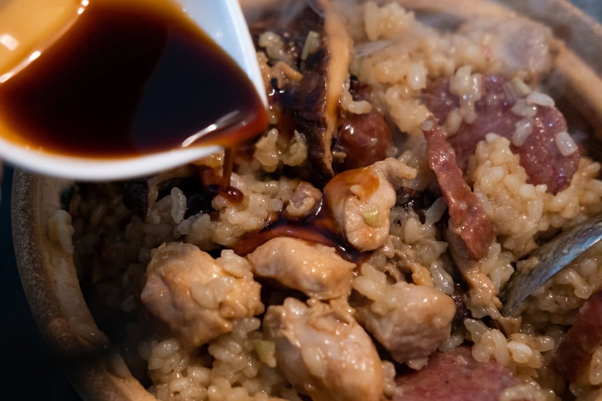 Adding soy sauce to claypot chicken rice. 