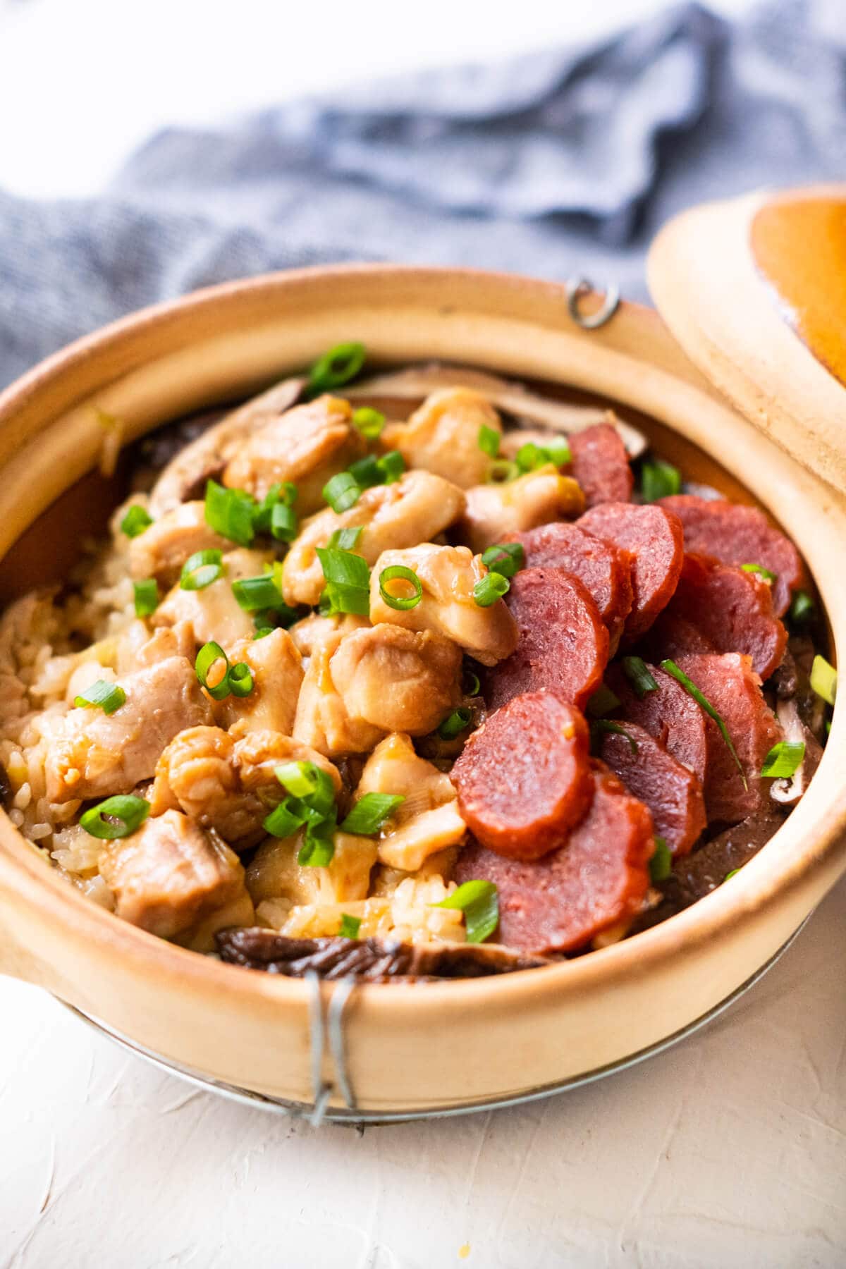 Malaysian claypot chicken rice with chicken pieces, mushrooms and sliced lap cheong in a claypot. 