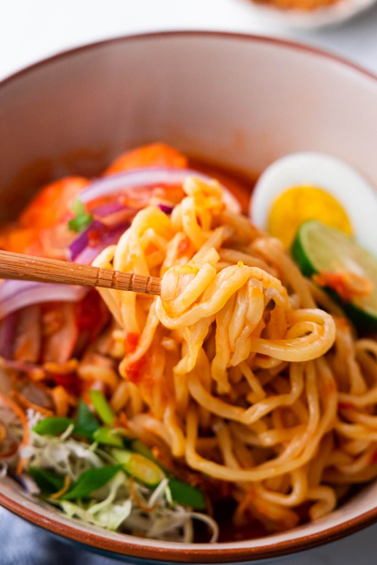 Mee udang yellow noodles picked up with chopsticks.