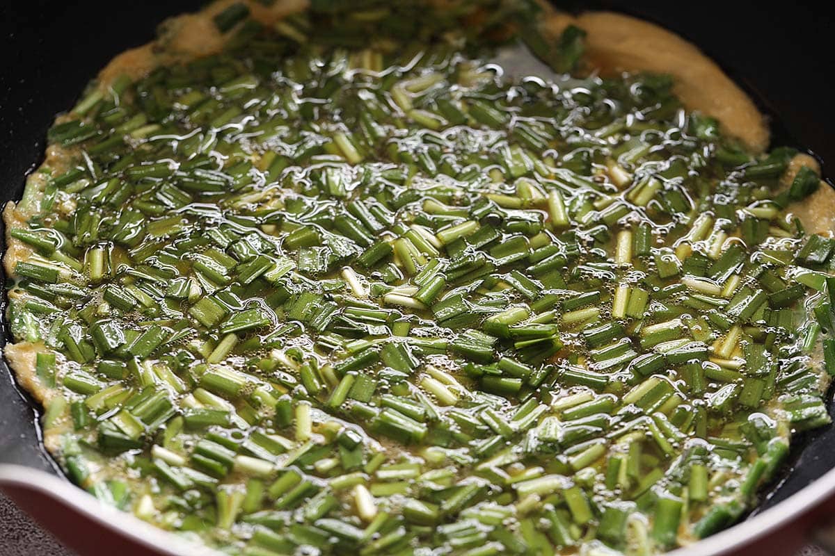 Cooking omelette with chives in a pan. 