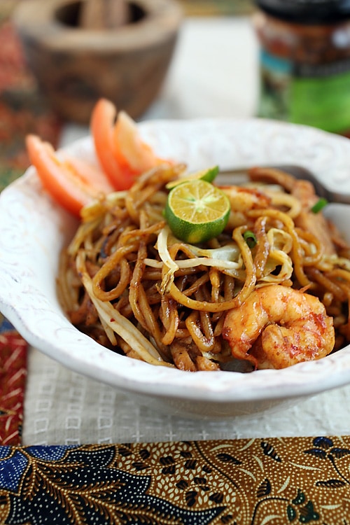 Delicious mi goreng in a plate, complete with chicken, shrimp, bean sprouts, and lime