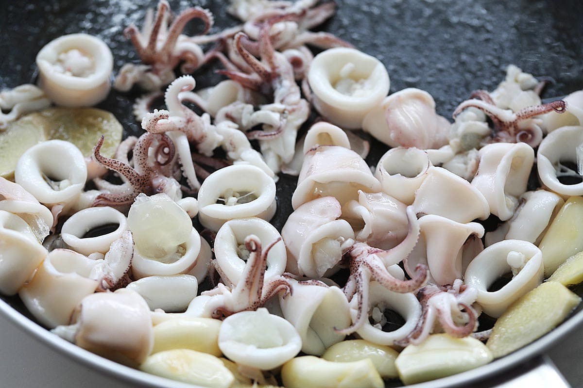 Stir frying squid with sesame oil, garlic and ginger in a skillet. 