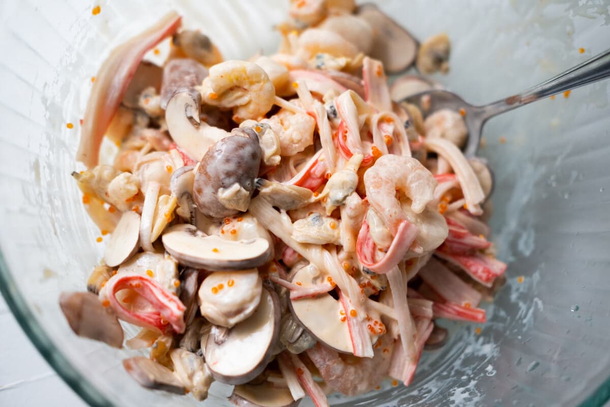 Baby shrimp, bay scallop, crab meat, clam, and sliced mushroom in a large bowl, mixed with dynamite sauce. 