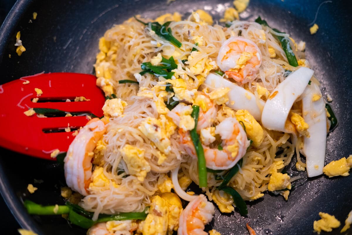 Add prawn, squid, chives and fry together with yellow noodle and rice vermicelli in the wok. 