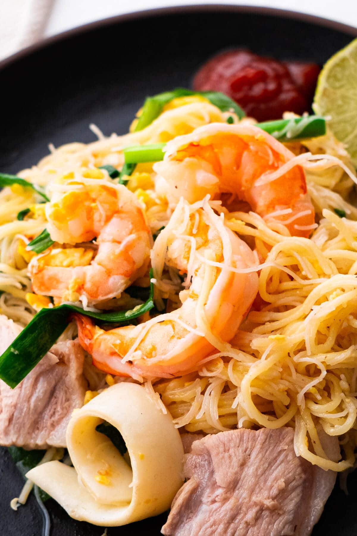 Stir-fried Singapore hokkien mee served with lime and sambal on the plate. 