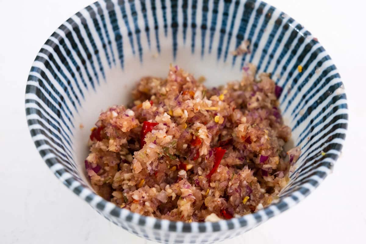 Paste made from blended red onion, ginger, galangal, lemongrass, chilies, and garlic, in a bowl.