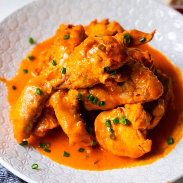 Ayam masak merah recipe served with chopped scallions on top.