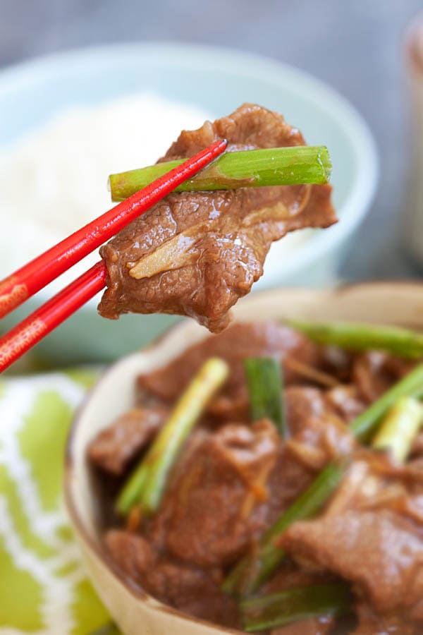 Ginger and scallion beef stir fry picked with a pair of chopsticks.