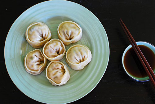 Top down view of Korean kimchi kalbi mandu served with a side of dumpling sauce.