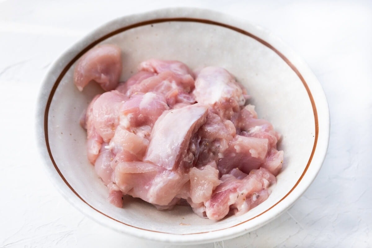 Chicken marinated with cornstarch in a bowl.