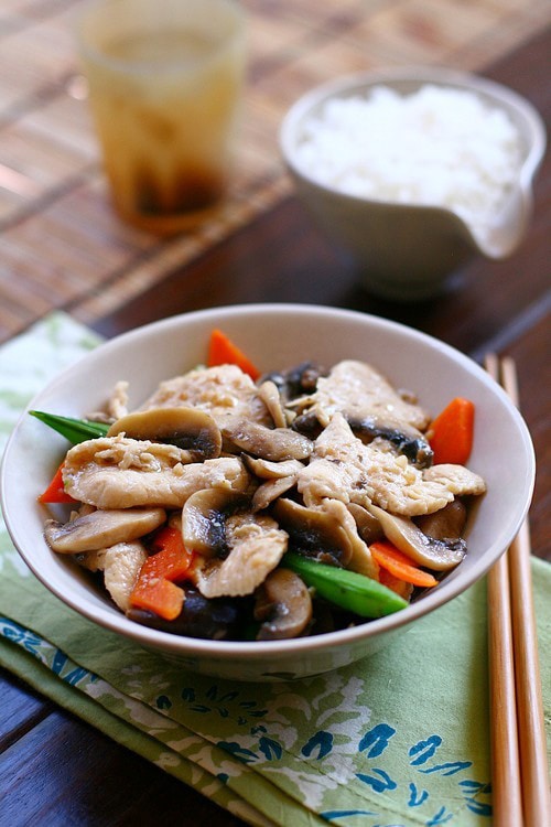 Authentic Asian Moo Goo Gai Pan chicken recipe with mushrooms and veggies in white sauce served with a bowl of rice.