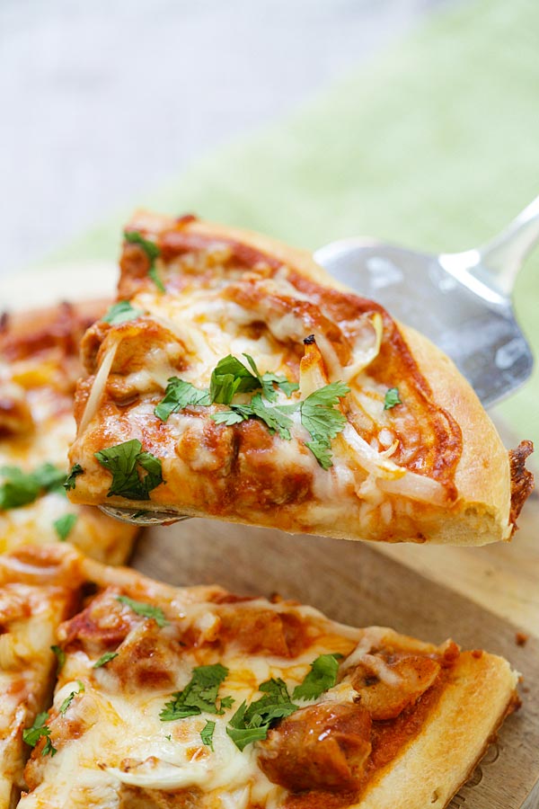 A piece of chicken tikka masala pizza picked up with a pizza shovel.