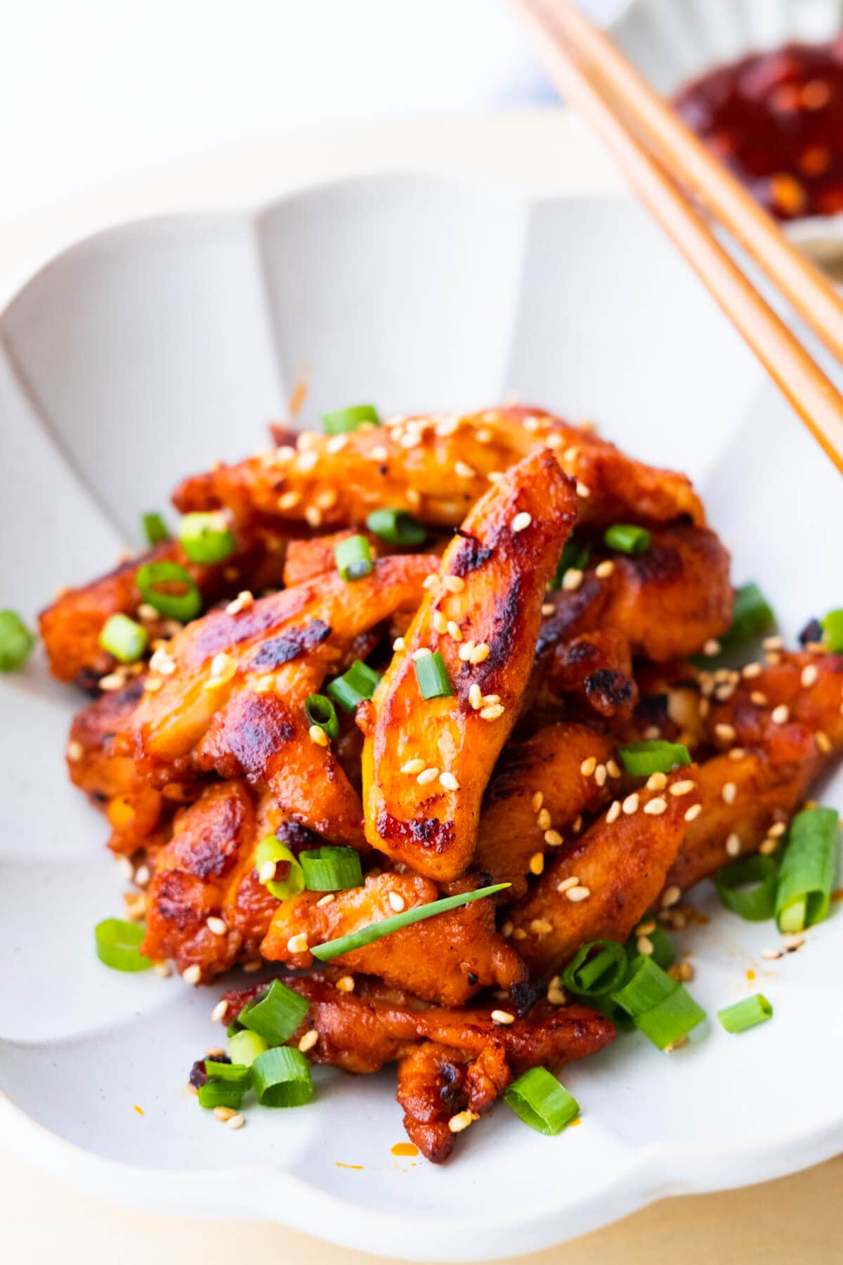 Korean spicy chicken recipe with white sesame seeds and chopped scallion on top. 