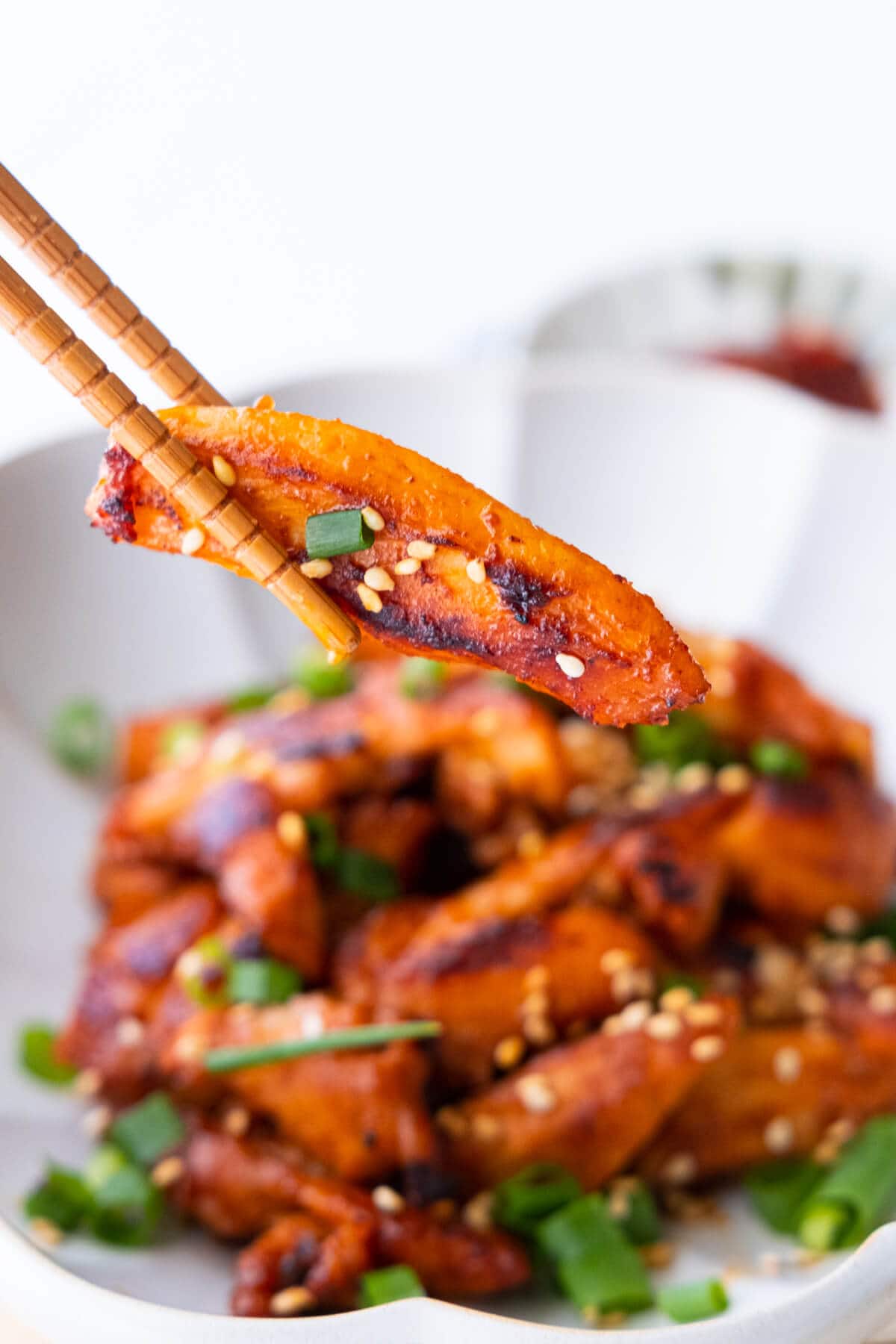 Stir fry Korean spicy chicken with a pair of chopsticks.
