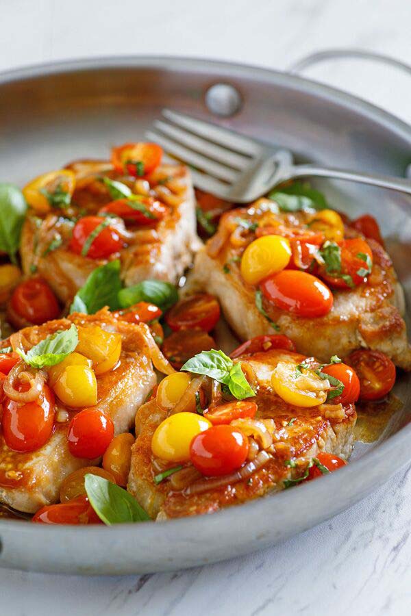 Easy homemade sauté sweet and sour Pork with cherry tomatoes in a skillet with a fork.