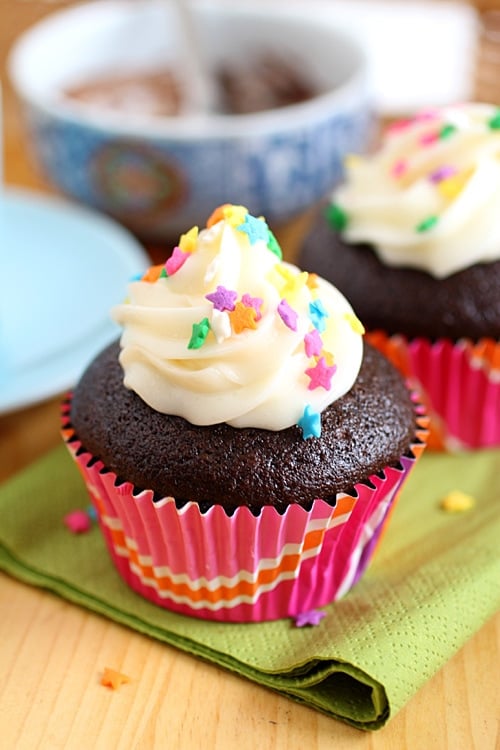 Chocolate cupcakes with ganache filling, frosting & sprinkles, ready to serve.