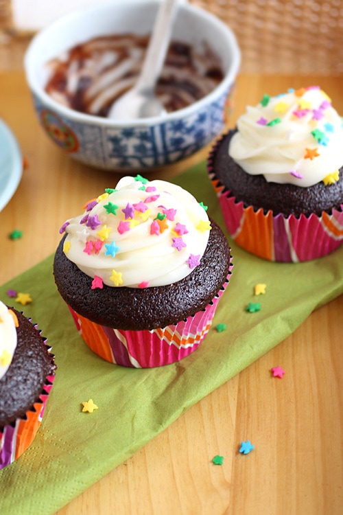 Mini homemade chocolate cupcakes with frostings and sprinkles.