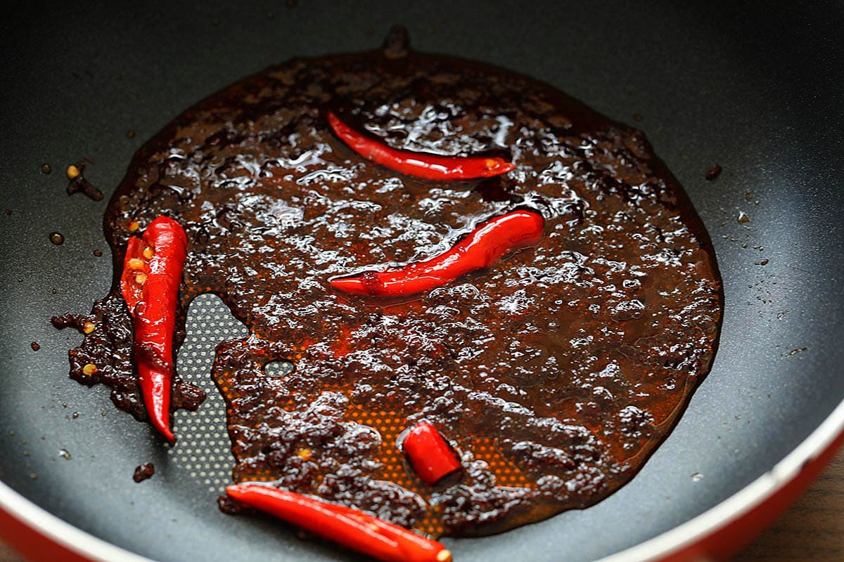 Sauteing nam prik pao with Thai chilies in a skillet. 