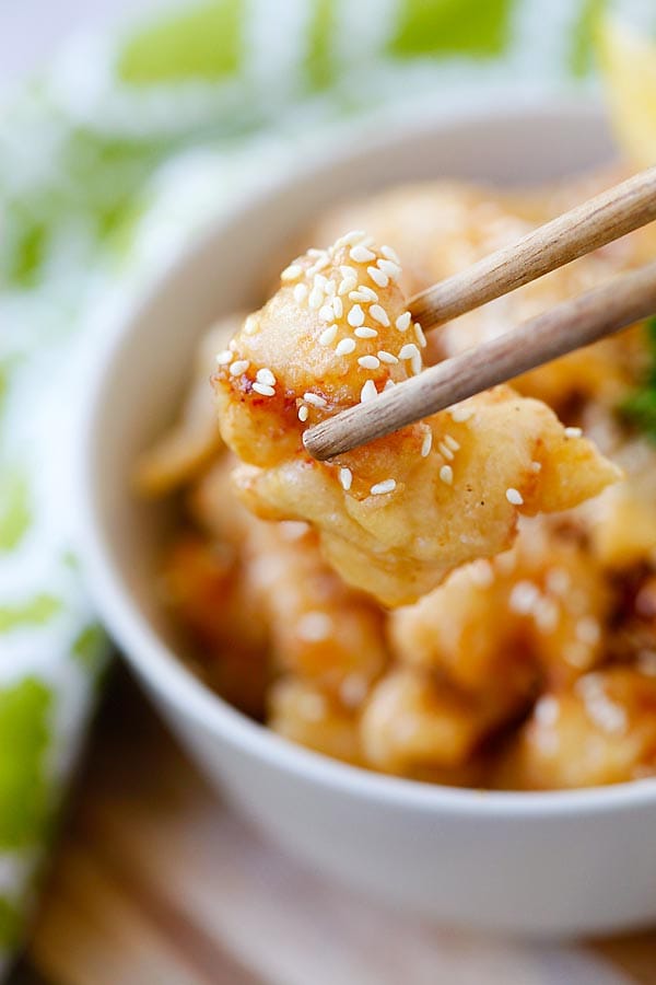 Asian lemon chicken with lemon sauce picked with a pair of chopsticks.