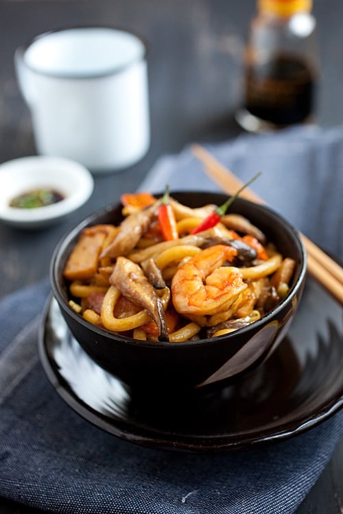 Malaysian easy stir fried thick noodles with cabbage, shrimp, fish cake in a dark brown sauce serve with cut chilies and soy sauce.